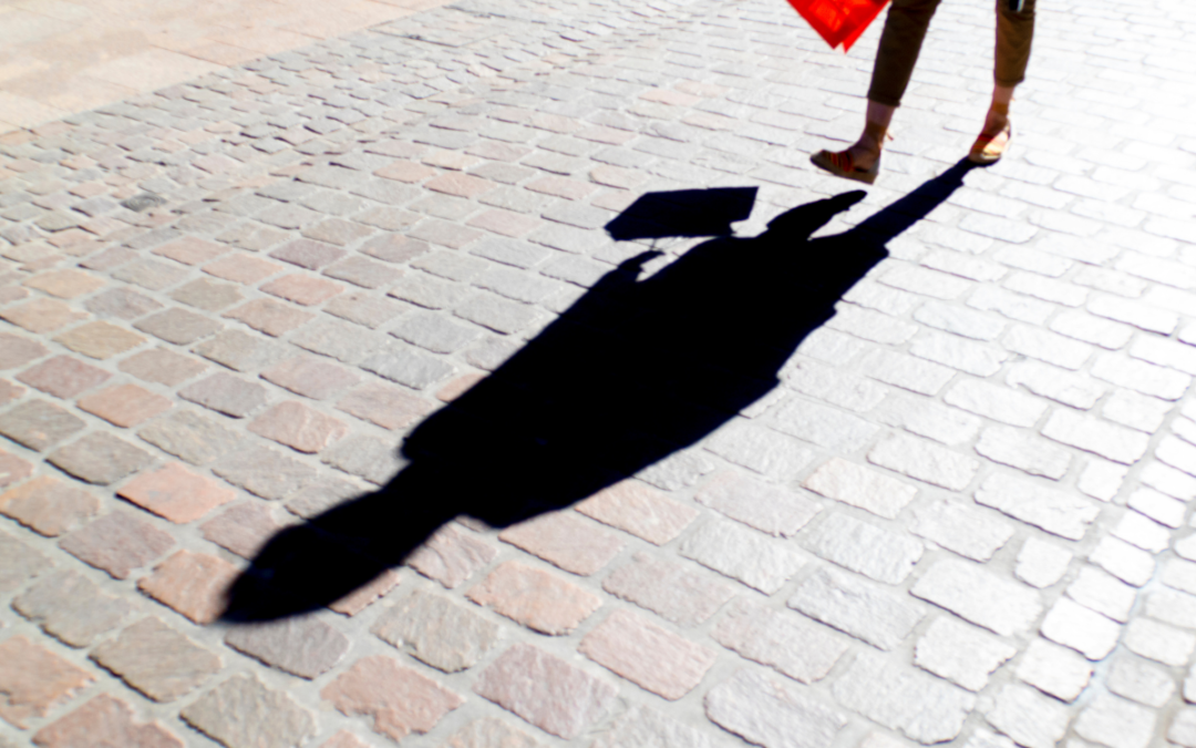 person walking in the sun and shadow on the ground in front of them